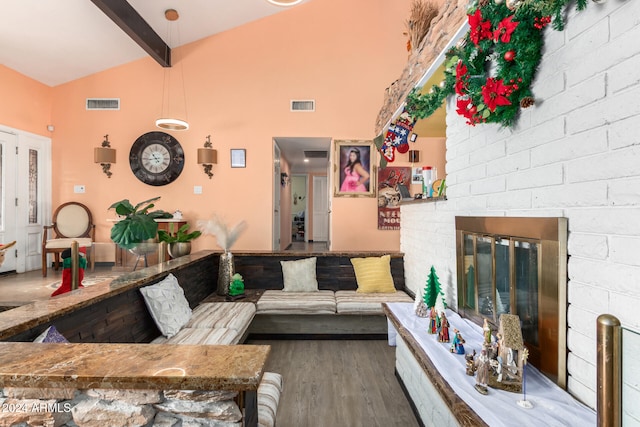 living room featuring lofted ceiling with beams, wood-type flooring, and a brick fireplace