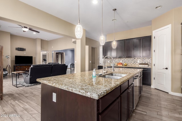 kitchen with dark brown cabinetry, a center island with sink, hanging light fixtures, and sink