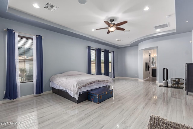 bedroom with a tray ceiling, ceiling fan, and light wood-type flooring