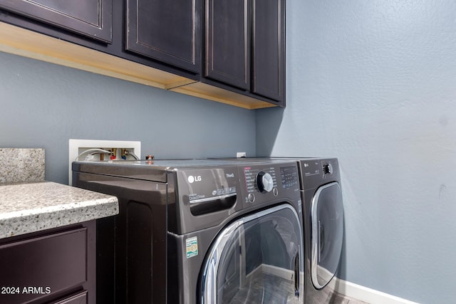 clothes washing area featuring cabinets and washer and clothes dryer