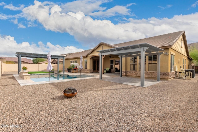 rear view of property with ceiling fan, a swimming pool with hot tub, a pergola, and a patio