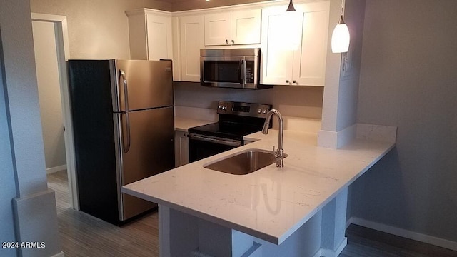 kitchen with sink, white cabinetry, hanging light fixtures, kitchen peninsula, and stainless steel appliances