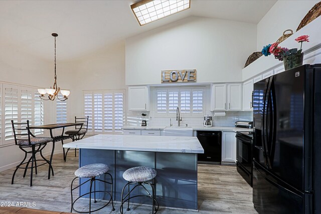 kitchen with a center island, black appliances, sink, light hardwood / wood-style flooring, and white cabinetry