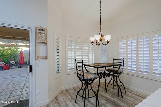 dining area featuring a high ceiling, hardwood / wood-style flooring, and a notable chandelier