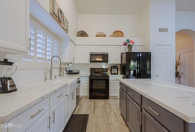 kitchen with light stone countertops, sink, white cabinetry, and black appliances