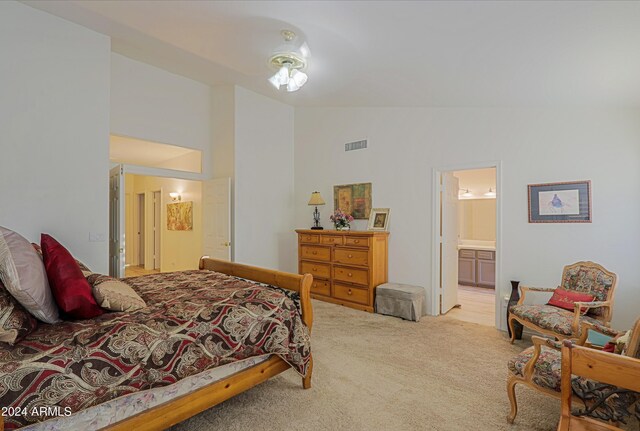 bedroom featuring ensuite bathroom, light colored carpet, and lofted ceiling