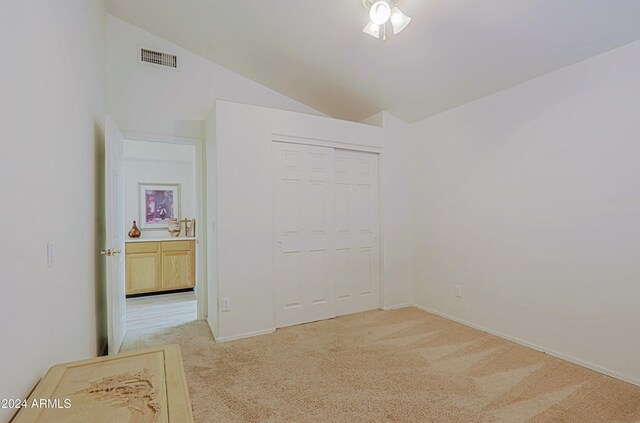 bedroom with ceiling fan, a closet, light colored carpet, and lofted ceiling