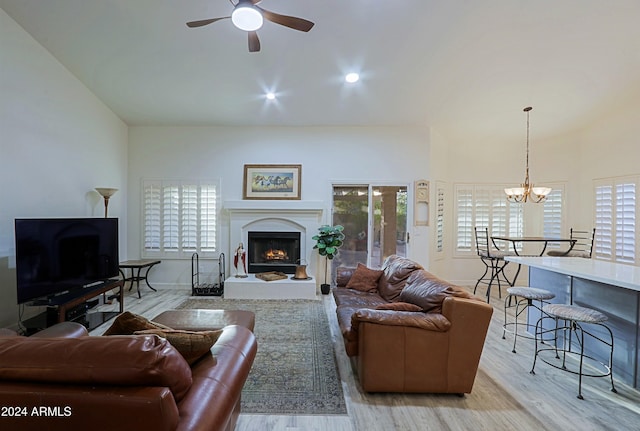 living room featuring light hardwood / wood-style flooring, a healthy amount of sunlight, and ceiling fan with notable chandelier