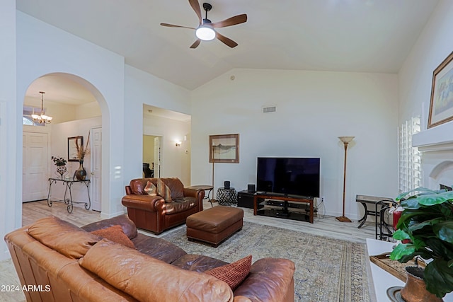 living room with ceiling fan with notable chandelier, light hardwood / wood-style floors, and high vaulted ceiling