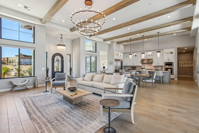 living room with baseboards, visible vents, beamed ceiling, light wood-type flooring, and a chandelier