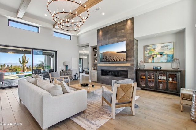 living room with visible vents, light wood finished floors, a high ceiling, beamed ceiling, and a notable chandelier