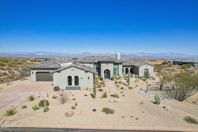 view of front of home with fence, driveway, a chimney, stucco siding, and a mountain view