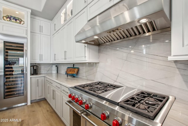 kitchen featuring white cabinetry, range hood, range with two ovens, and wine cooler