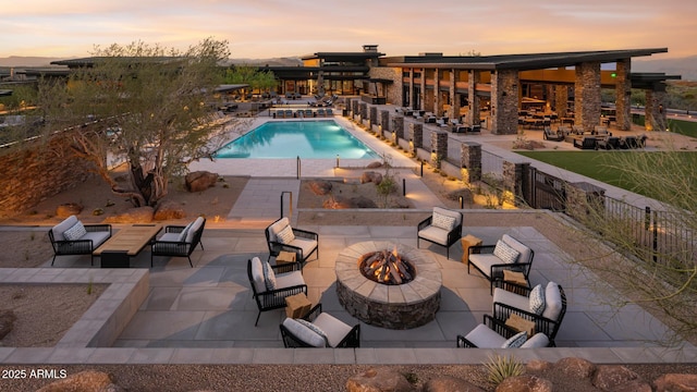 pool with a patio, a fire pit, and fence