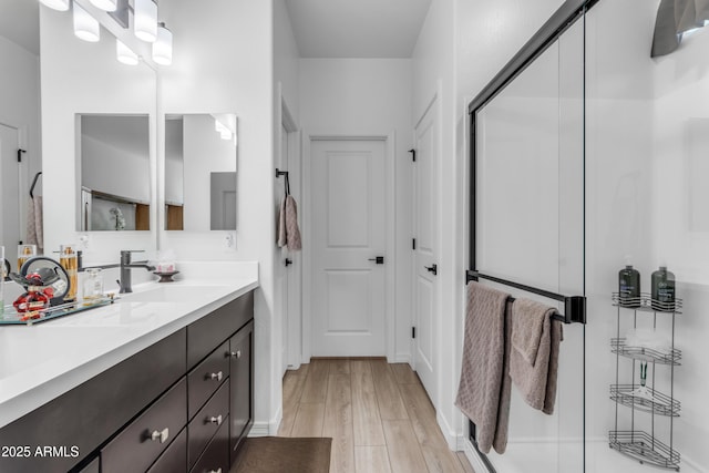 bathroom with walk in shower, vanity, and hardwood / wood-style floors