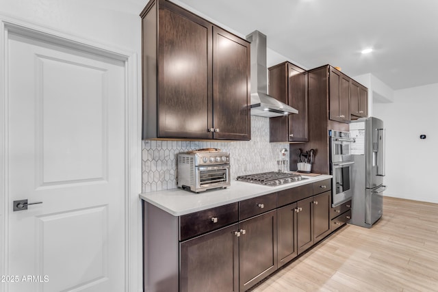 kitchen with stainless steel appliances, dark brown cabinetry, and wall chimney exhaust hood