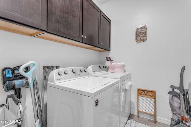 clothes washing area featuring cabinets, light wood-type flooring, and washer and clothes dryer