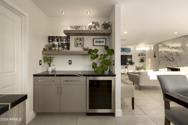 bar featuring gray cabinetry, light tile patterned floors, and beverage cooler