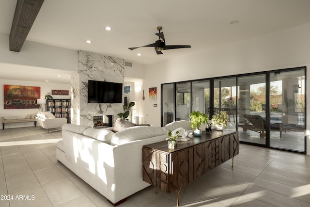 living room with ceiling fan, beam ceiling, light tile patterned flooring, and a premium fireplace