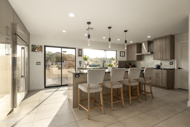 kitchen with pendant lighting, wall chimney exhaust hood, a healthy amount of sunlight, and a kitchen island