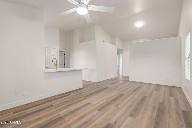 unfurnished living room featuring ceiling fan, light hardwood / wood-style floors, high vaulted ceiling, and sink