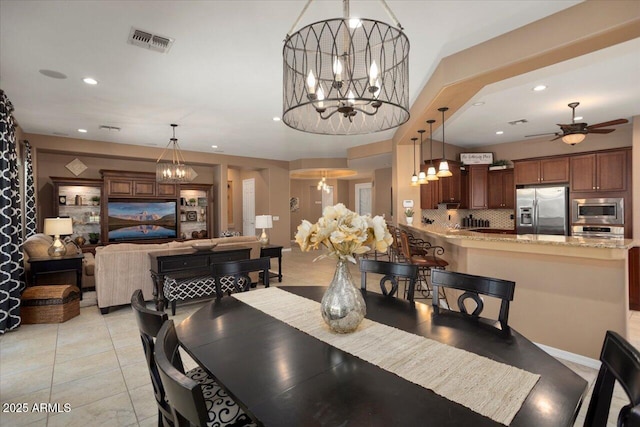 dining room with ceiling fan with notable chandelier and light tile patterned floors