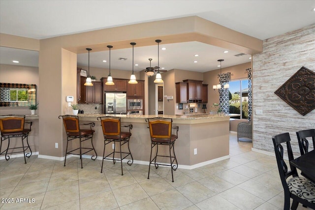 kitchen featuring pendant lighting, stainless steel appliances, kitchen peninsula, and a breakfast bar