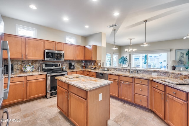 kitchen featuring hanging light fixtures, light stone counters, stainless steel appliances, sink, and a notable chandelier