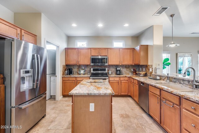 kitchen with a wealth of natural light, a center island, appliances with stainless steel finishes, and sink