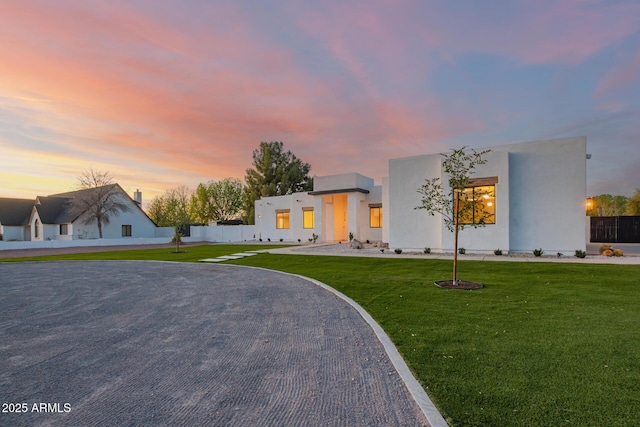 contemporary home featuring fence, a front lawn, and stucco siding