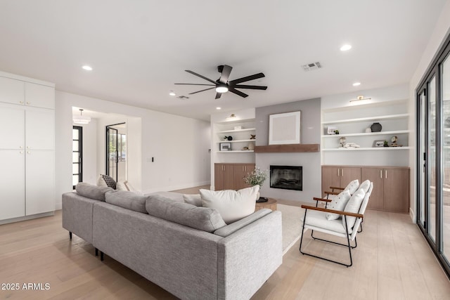 living area featuring light wood-type flooring, a fireplace, visible vents, and recessed lighting