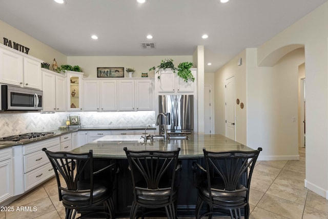 5122 S Miller Pl, Chandler, AZ 85249 - kitchen featuring stainless steel appliances, dark stone countertops, tasteful backsplash, a breakfast bar area, and visible vents