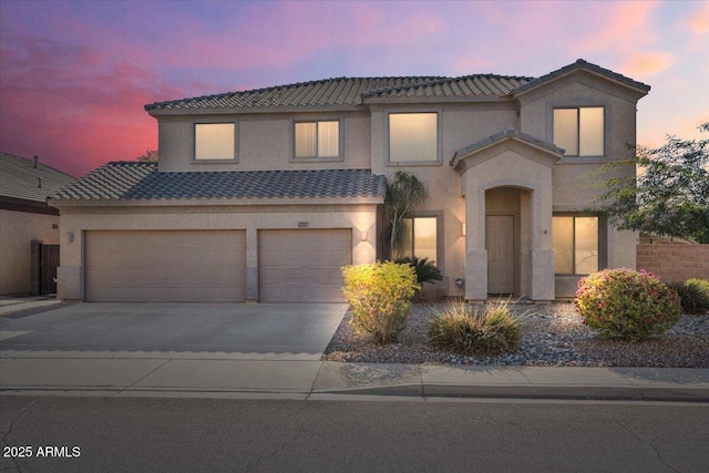 view of front facade featuring a garage, a tile roof, driveway, and stucco siding