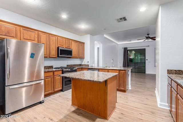 kitchen with stainless steel appliances, kitchen peninsula, light hardwood / wood-style flooring, and a kitchen island