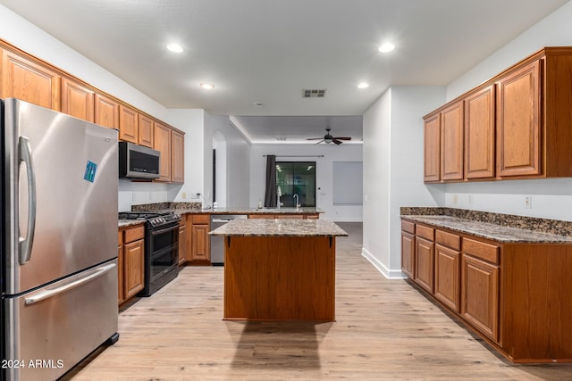 kitchen featuring a kitchen island, stone counters, light hardwood / wood-style floors, and stainless steel appliances