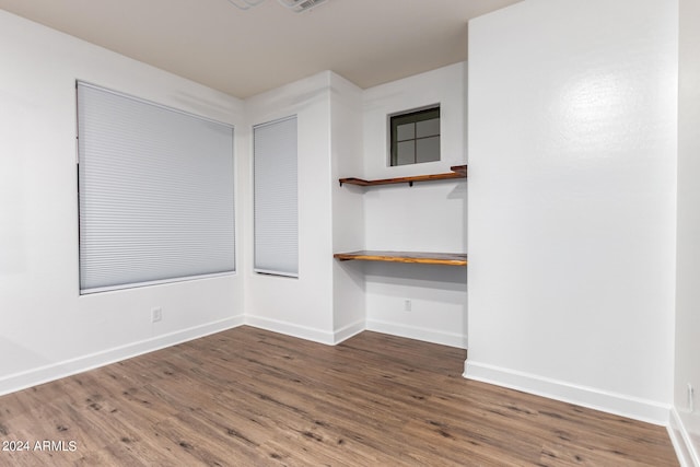 spare room featuring wood-type flooring and built in desk