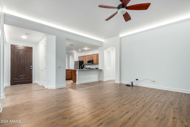 unfurnished living room featuring ceiling fan, sink, and light hardwood / wood-style flooring