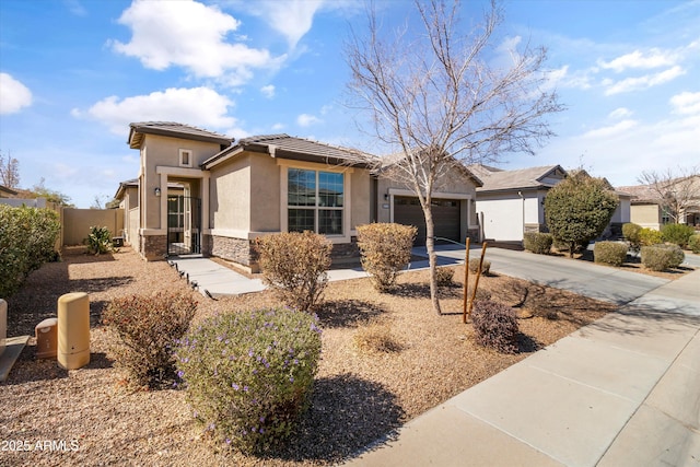 view of front of home featuring driveway, stone siding, an attached garage, fence, and stucco siding