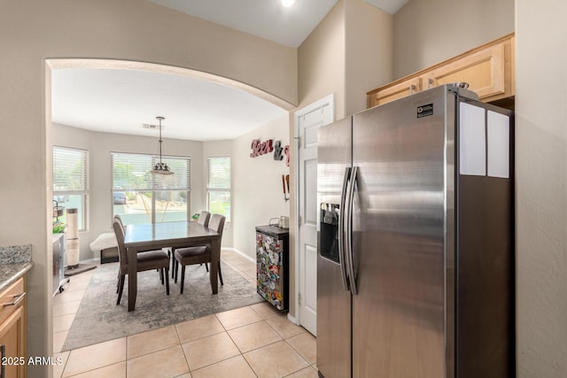 1634 E Harwell Rd, Phoenix, AZ 85042 - kitchen featuring stainless steel fridge, arched walkways, light brown cabinetry, light tile patterned floors, and pendant lighting