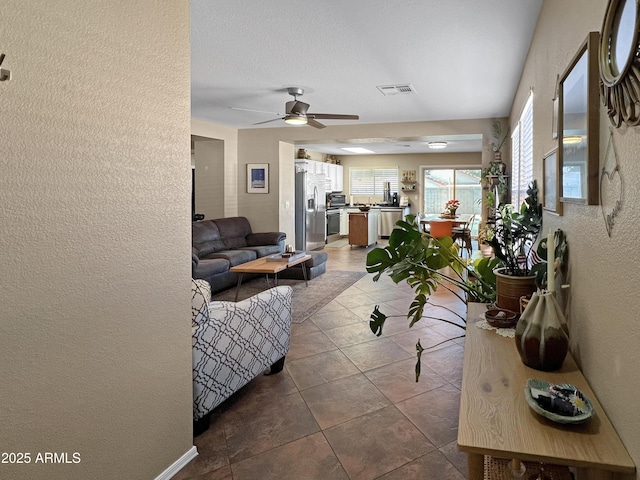 tiled living room featuring a textured ceiling and ceiling fan