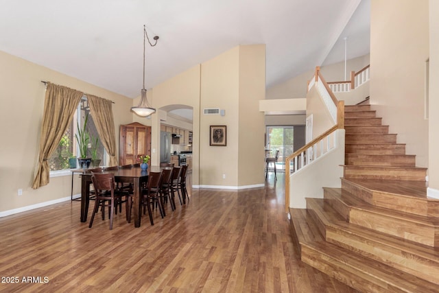 5215 W Del Rio St, Chandler, AZ 85226 - dining space with arched walkways, wood finished floors, high vaulted ceiling, and stairs