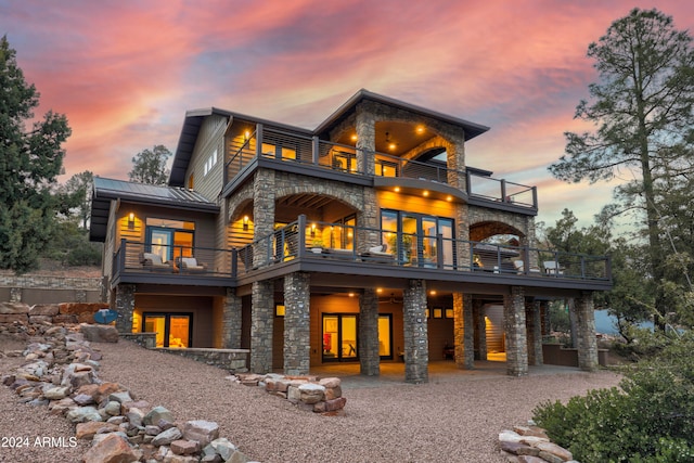 back house at dusk featuring a balcony