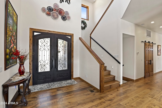 entryway with hardwood / wood-style flooring, a barn door, and french doors