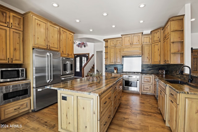 kitchen with dark hardwood / wood-style flooring, stainless steel appliances, a kitchen island, and sink