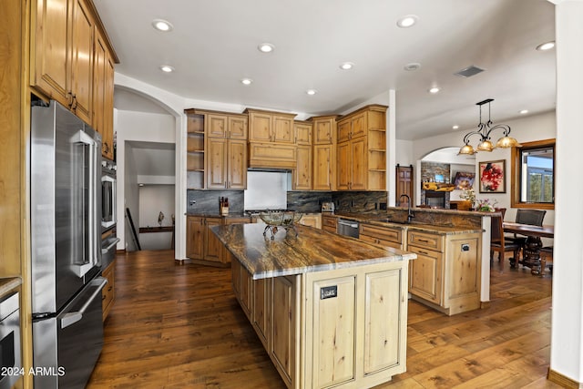 kitchen featuring a center island, dark wood-type flooring, stainless steel appliances, and pendant lighting