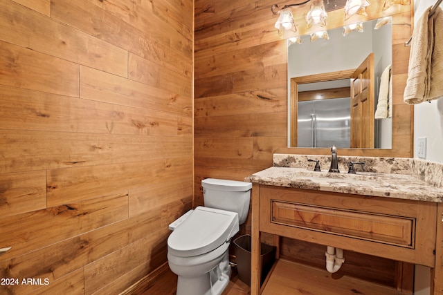 bathroom featuring wooden walls, vanity, wood-type flooring, and toilet