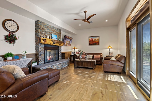 living room with a fireplace, ceiling fan, and light wood-type flooring