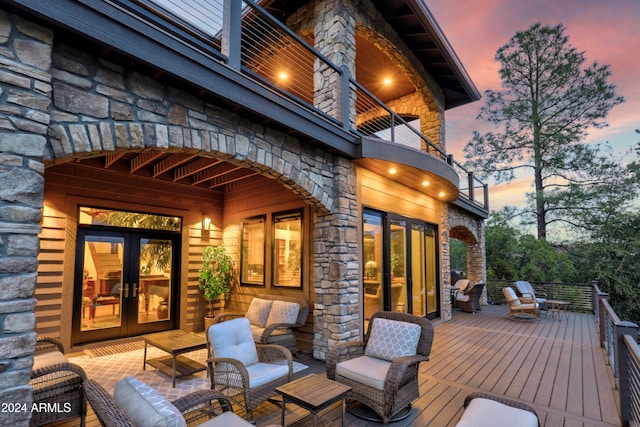 deck at dusk with french doors and an outdoor living space