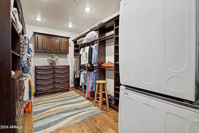 walk in closet featuring stacked washer and dryer and light hardwood / wood-style floors