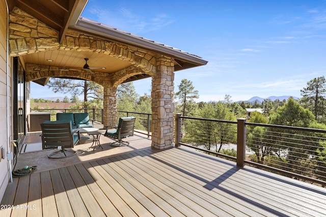 wooden deck with outdoor lounge area, a mountain view, and ceiling fan